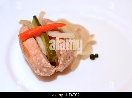 Teil einer traditionellen tschechischen eingelegte Wurst in sauren Sole mit Gurke, Zwiebeln und roten Peperoni. Stockfoto