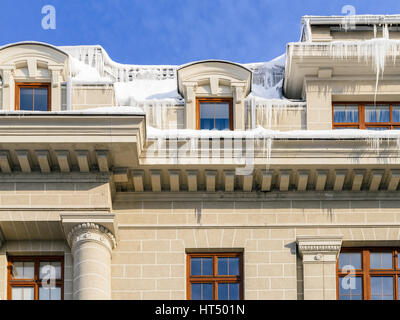 Hausdach bedeckt mit Schnee und gefährliche Eiszapfen Stockfoto
