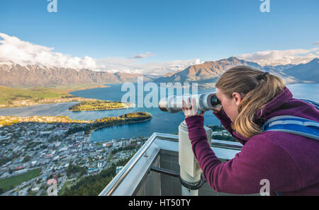 Frau auf der Suche durch Teleskop, Ansicht des Lake Wakatipu und Queenstown aus die Skyline Gondola, Gondel-Seilbahn Stockfoto