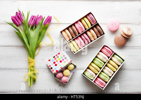 Tulpen und Boxen mit Macarons auf Holztisch Stockfoto