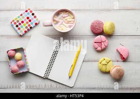 Heiße Schokolade, Süßigkeiten und Copybook auf Holztisch Stockfoto