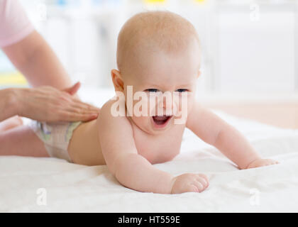 Frau Arzt Massage Baby im Bett im Kinderzimmer Stockfoto