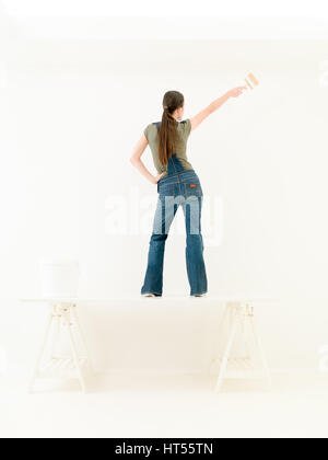Fröhlich tanzende Frau mit Malerei Pinsel auf dem Tisch Stockfoto
