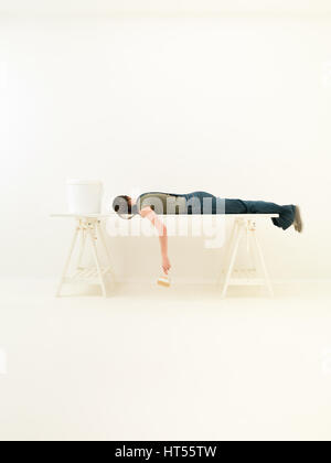 Lustige DIY Konzept Bild Frau schläft auf einem Tisch mit einem Pinsel in der hand Stockfoto