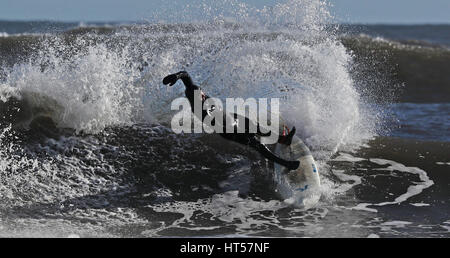 Eine Surfer reitet die rauen Wellen in Whitley Bay. Stockfoto