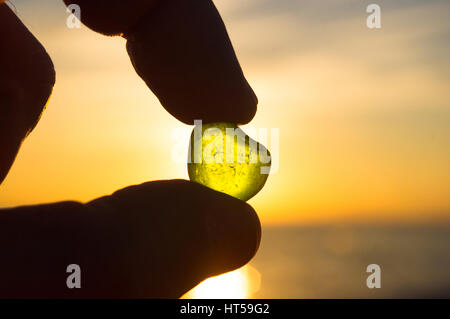 das Meer geglättet grünes Glas in der Hand auf Hintergrund des Sonnenuntergangs Stockfoto