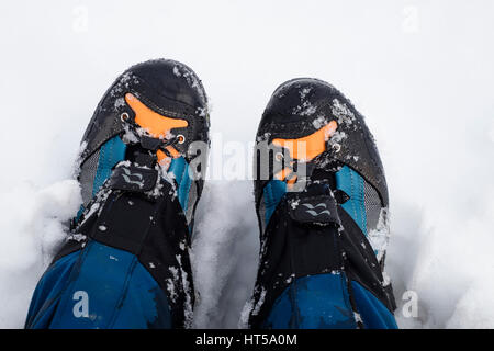 Nahaufnahme von einem Wanderer Beine tragen von einem Paar aus Stoff und Leder Wanderschuhe und Gamaschen im Schnee von oben gesehen. UK, Großbritannien. Stockfoto