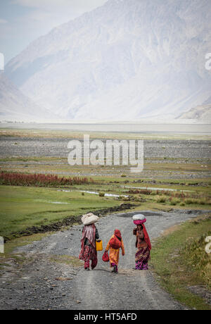 Afghanistan, Wakhan-Korridor, Frauen in bunten Trachten zu Fuß durch das Tal zwischen den Bergen. Stockfoto