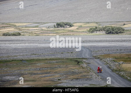 Afghanistan, Wakhan-Korridor, Frauen in bunten Trachten zu Fuß durch das Tal zwischen den Bergen. Stockfoto