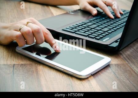 Frau mit Tablet und Laptop auf hölzernen Hintergrund Stockfoto