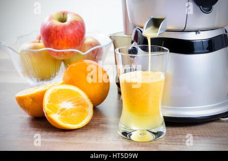 Entsafter und Orangensaft. Früchte im Hintergrund Stockfoto