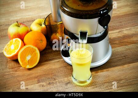 Entsafter und Orangensaft auf hölzernen Hintergrund Stockfoto