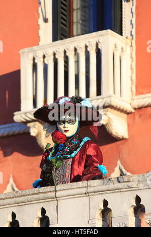 Eine maskierte Frau in einem traditionellen venezianischen Kleid mit einer roten rose während 2017 Karneval von Venedig, Italien Stockfoto