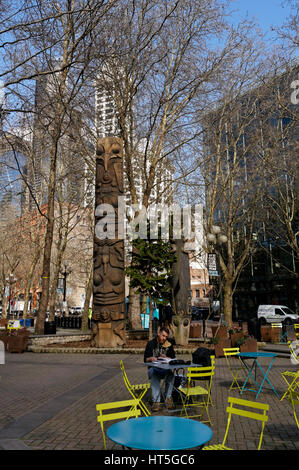 Bärtiger jungen Mann Lesung auf einen Tisch im Freien am Occidental Square Park in den Pioneer Square District von Seattle, Washington, USA Stockfoto