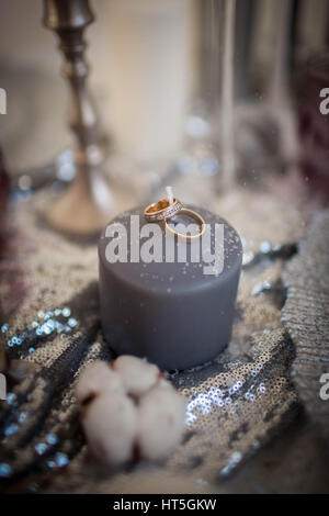 Trauringe auf eine Kerze. Dekorationen, bestreut mit Schnee. Hochzeit Urlaub. Stockfoto