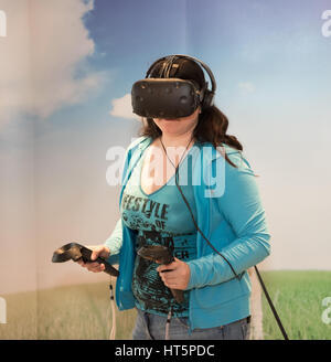 Virtuelle Realität wird durch eine Frau erfahren Sie beim Tragen des Headsets und Verwenden von Controllern. Stockfoto