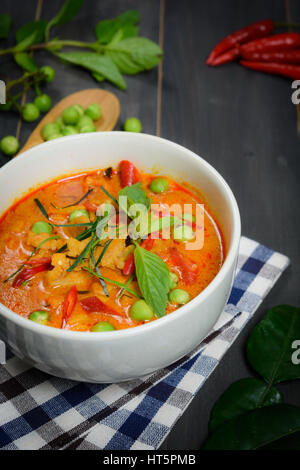 Closeup Panaeng Curry mit Schweinefleisch oder rotem curry mit Schweinefleisch (Panang Schweinefleisch) auf Holztisch mit Tisch Tuch und Gemüse Draufsicht Stockfoto