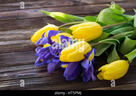 Bouquet von gelben Tulpen und Iris Blumen auf einem Holztisch, Sonnenstrahlen fällt auf den Hintergrund. Detailansicht. Womens Tag, Mütter Tag Konzept Stockfoto