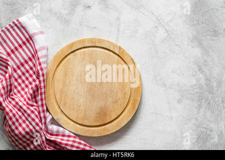 Alte Runde Holzbrett und rot karierten Tischdecke auf grauem Beton Hintergrund mit textfreiraum für Text. Pizza-board Stockfoto