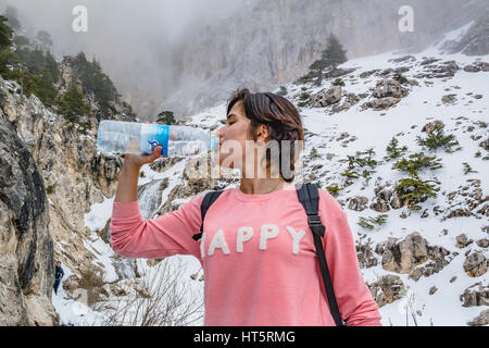 durstig Mädchen Trinkwasser im Winter auf dem Schneeberg Stockfoto