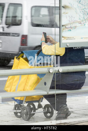 weibliche Briefträgerin in Uniform mit Zusammenstellung Bus warten. Stockfoto