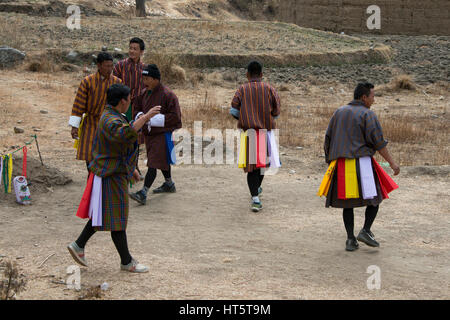 Bhutan, Paro. Khuru (Darts) traditioneller bhutanische Sport werfen große Dart im Freien. Spieler in traditioneller Kleidung dabei einen Tanz wenn jemand Hallo Stockfoto