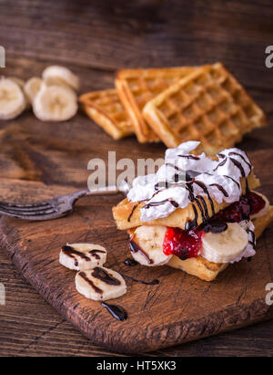 Belgische Waffeln mit Bananen und Sahne auf rustikalen Tisch. Stockfoto