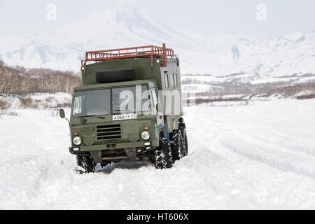 Alte schwedische militärische Geländewagen Volvo Laplander C304 (sechs-Rad-Antrieb) Khaki Farbe, fahren im Schnee entlang einer Landstraße auf Hintergrund Vulkane Stockfoto