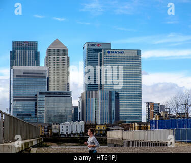 Sonntag, 5. März 2017, North Greenwich, London: Eine einsame Frau Jogger auf dem gegenüberliegenden Ufer der Themse von den Canary Wharf Towers besetzt von m Stockfoto