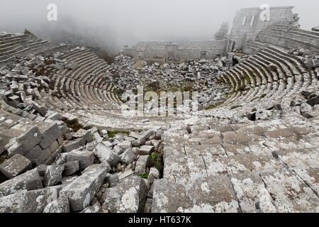 Ruinen des hellenistisch-römischen Theaters unter dem Nebel mit halbrunden Sitzgelegenheiten Bereich-Cavea 24 Sitzreihen und Diazoma plus Bühne Gebäude-Podium-Orch Stockfoto