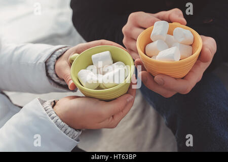 Close-up Portrait von Mann und Frau halten in ihren Händen gelbe und grüne Cup, in dem süßen Marshmallow liegt Stockfoto