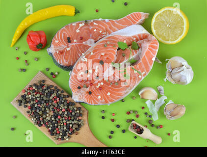 Frische Lachs-Steaks mit Gewürzen auf grüne Küche Matte umgeben Stockfoto