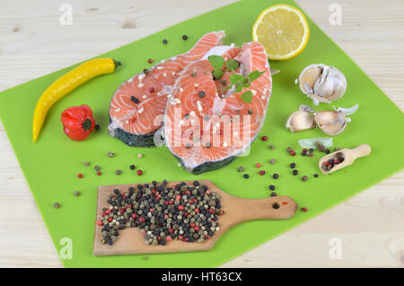 Frisch und saftig-Lachs-Steaks mit Gewürzen, Zitronensaft und Knoblauch auf grüne Küche Matte umgeben Stockfoto