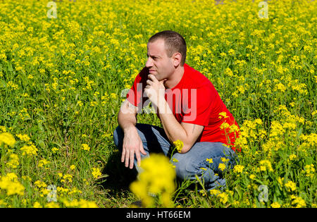 Mann in einem Feld von gelben Blüten denken was morgen hält. Stockfoto