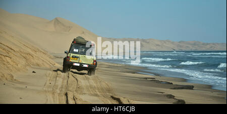 Ein Fahrzeug, das die Flut zwischen den Dünen und dem Meer zu Sandwich Harbour in Namibia zu fahren. Stockfoto