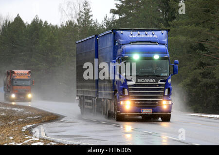 SALO, Finnland - 4. März 2017: Blaue Scania R620 Kombination Fahrzeug von M. Keskimaki und ein weiterer LKW Transport von waren auf nasser Fahrbahn bei Schneefall. Stockfoto