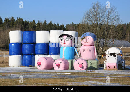 LIETO, Finnland - 5. März 2017: Stilleben auf ein Feld aus der Silageballen von unbekannten mit der Flagge von Finnland, der Landwirt paar und Bauernhof-Tier Stockfoto