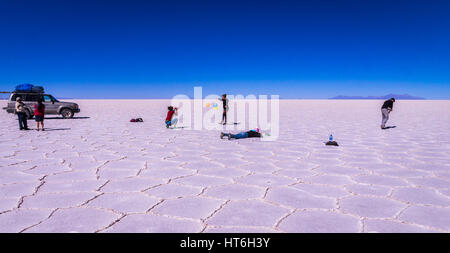 Salar de Uyuni, Bolivien am 21. September 2015: Touristen neben Jeep die lustige Fotos am Salzsee Stockfoto