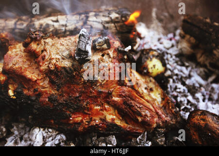 Backen Lamm, Bein und Kartoffeln auf Kohlen im freien Stockfoto