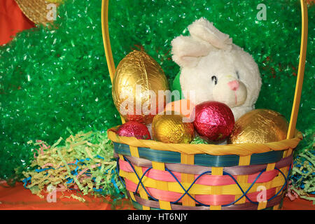 Ein Bild zeigt das Konzept der Ostern mit einem Korb voller Eier und ein weißer Hase Stockfoto