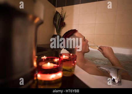 schöner junger Mann genießt, entspannen im Whirlpool mit Kerzen und Champagner im Luxus-Resort-spa Stockfoto