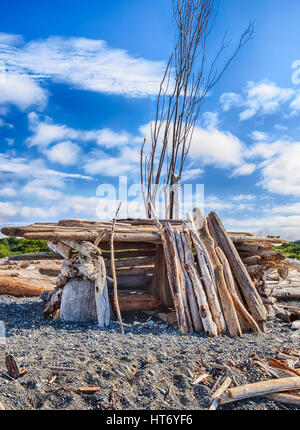 Eine kleine hausgemachte Struktur mit einem Eingang, gebaut aus Treibholz an einem Strand im Puget Sound, bietet Schutz vor dem Wind. Stockfoto