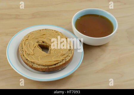 Erdnussbutter auf Bagel auf Snack Teller und Honig in kleinen Gewürz-Schüssel Stockfoto
