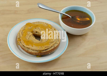 Erdnussbutter auf Bagel auf Snack Teller und Honig in kleinen Gewürz-Schüssel Stockfoto