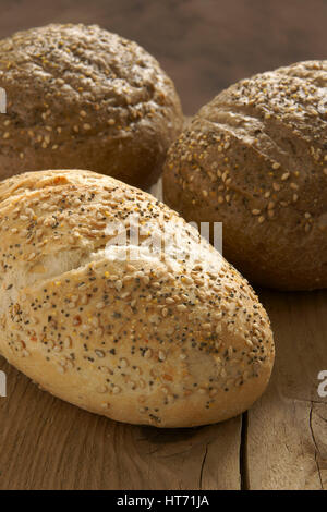 Rustikale Vollkorn Brote auf einem hölzernen Brot-Brett Stockfoto