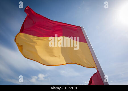 WOOLACOMBE, UK - 19 Mai: Eine rote und gelbe Wimpel flattern im Wind gegen ein strahlend blauer Himmel am Strand von Woolacombe am 19. Mai 2011. Die Flagge Stockfoto