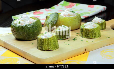 Lachs-Creme gefüllte Zucchini (Zucchini) auf ein Holzbrett auf bunten Küche Tücher - Gemüse und Meeresfrüchte Rezept - selektiven Fokus liegen Stockfoto