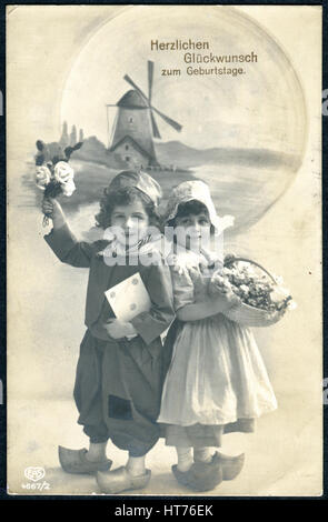 Eine Gruß-Postkarte gedruckt in Deutschland, zeigt einen jungen und ein Mädchen mit Blumen im holländischen Trachten: die Inschrift auf Deutsch: alles Gute zum Geburtstag Stockfoto