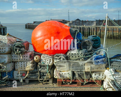 Eine große helle orange Boje auf hausgemachten Angeln Kanister punktiert mit Löchern mit Seilen und Netzen im Dock auf der Whitstable Hafen, Kent Stockfoto