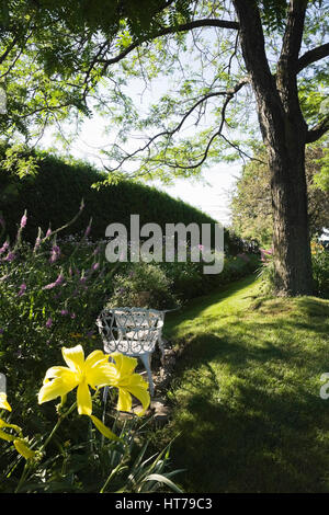 Weißes Gusseisen viktorianischen Garten Stühle und Tisch in einem angelegten Garten im Sommer. Stockfoto